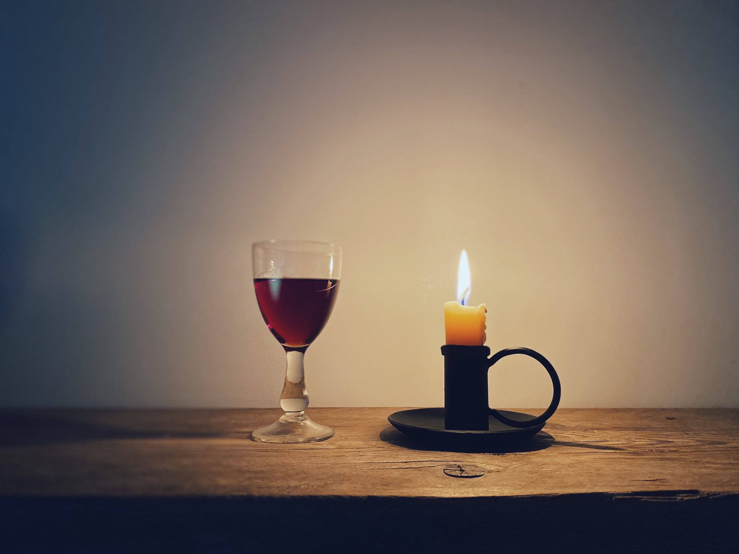 a burning candle and glass of sloe gin